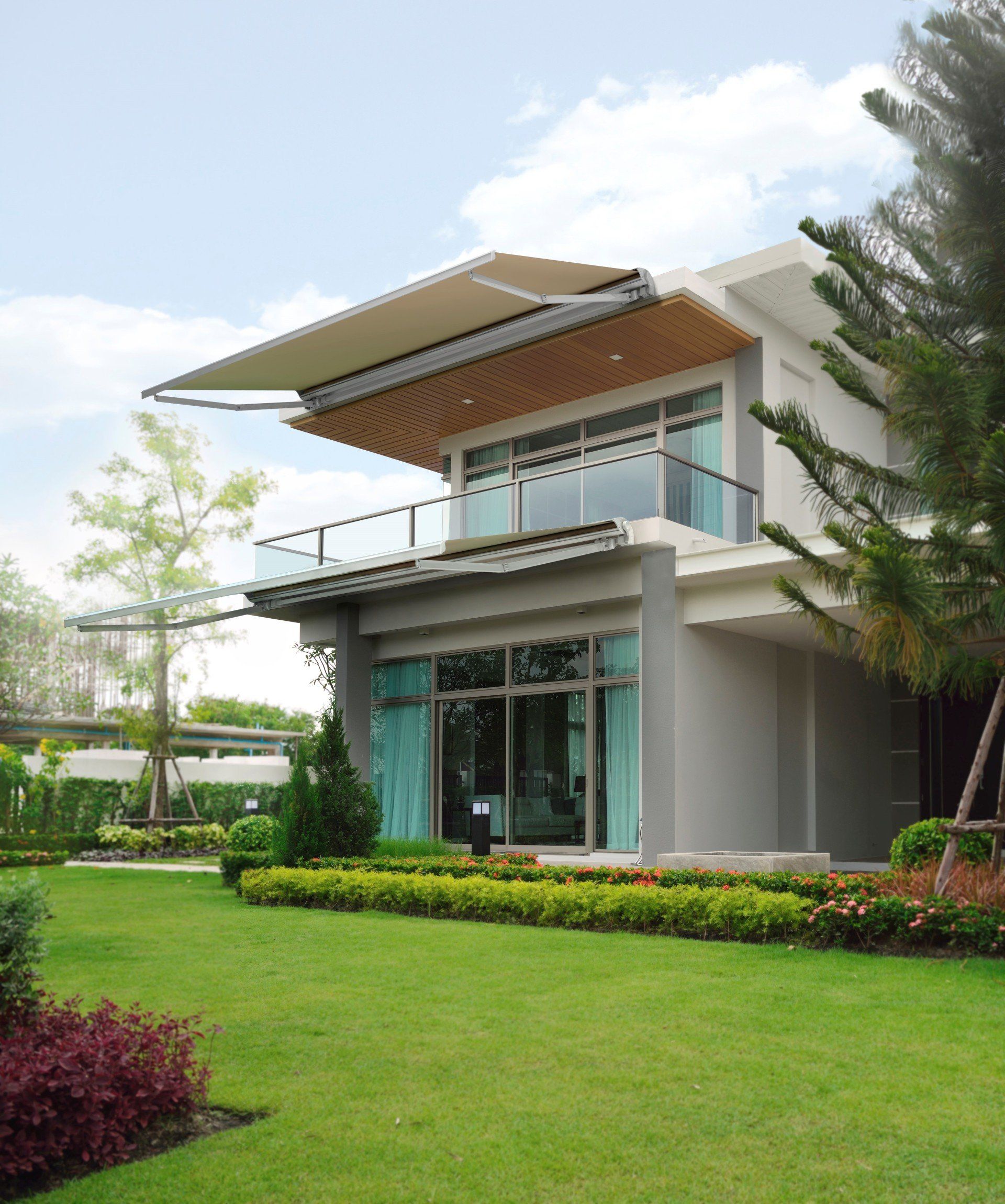 A large house with a balcony and a lush green lawn in front of it