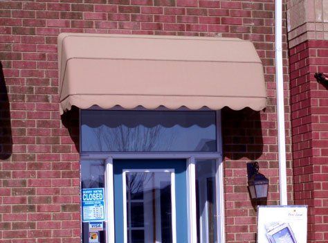 A brick building with a tan awning over the door