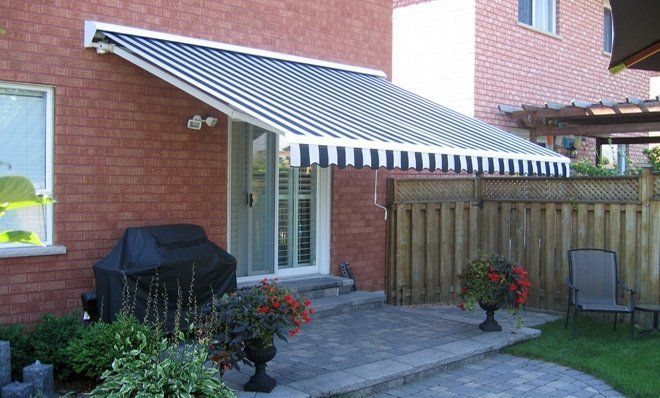 A black and white awning is on the side of a brick house.