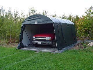 A red truck is parked in a garage under a tent.