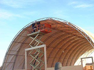 A man on a scissor lift is working on a large dome.