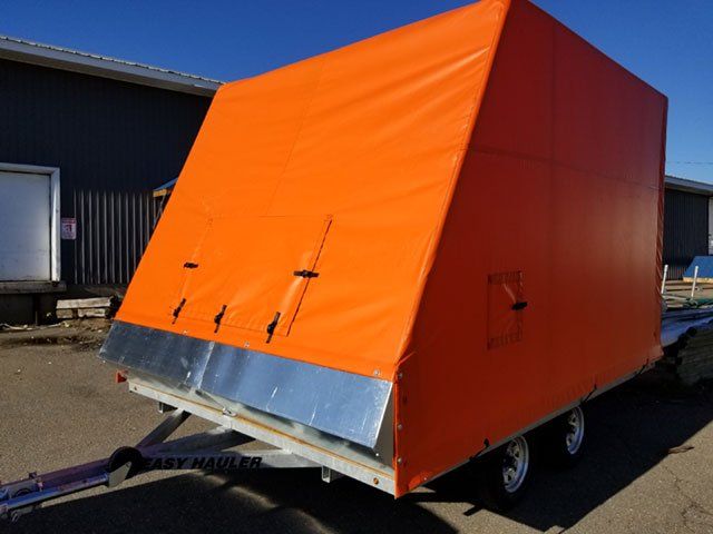 An orange trailer is parked in front of a building