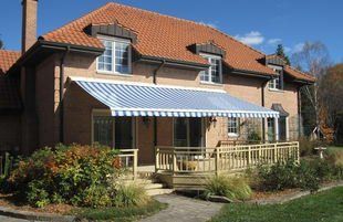 A large brick house with a blue and white awning on the porch.