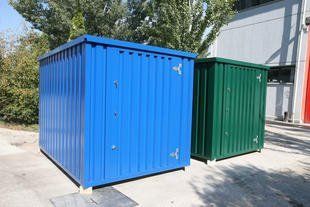 Two blue and green containers are sitting next to each other in a parking lot.