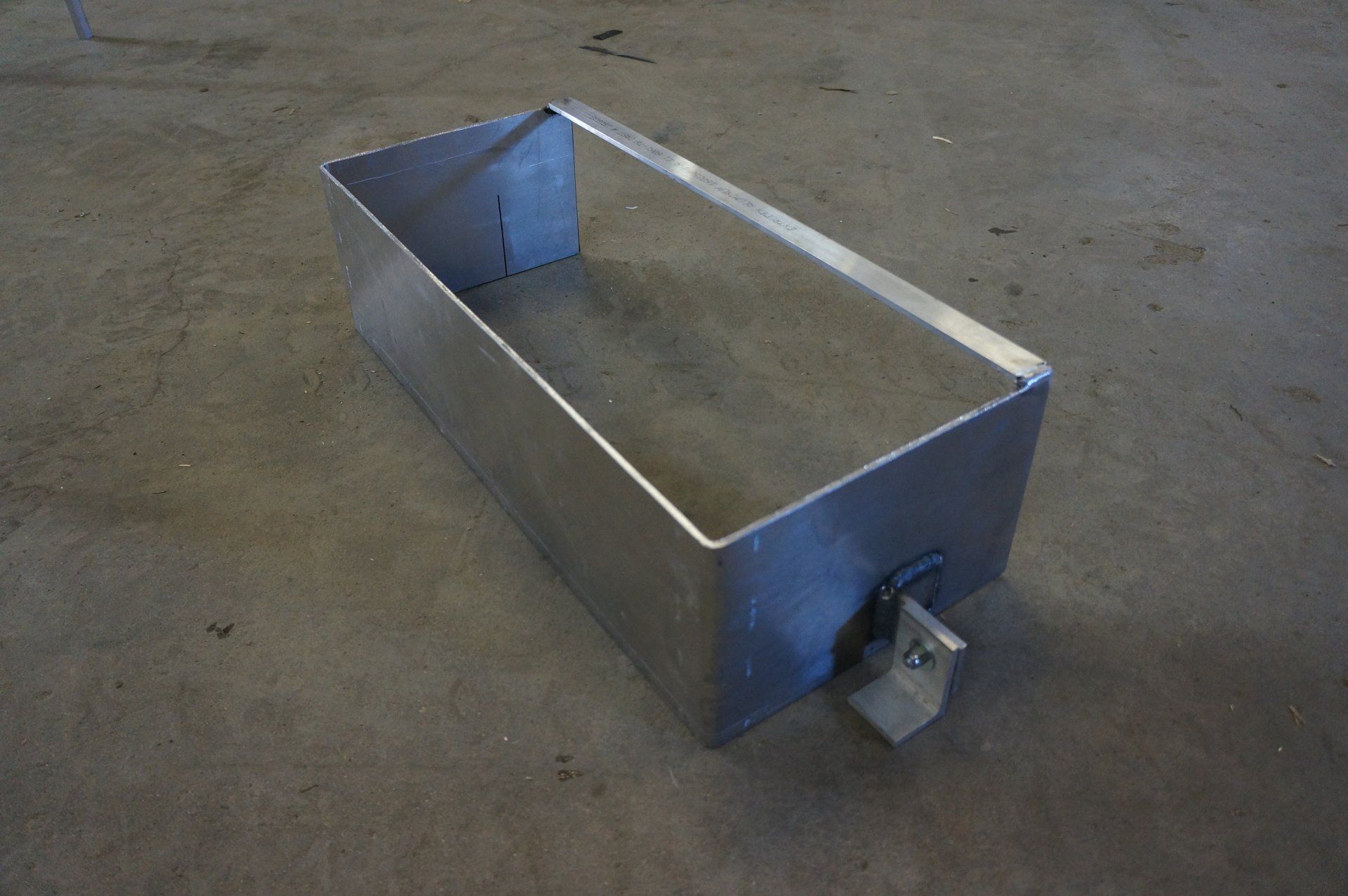 A metal box is sitting on a concrete floor.