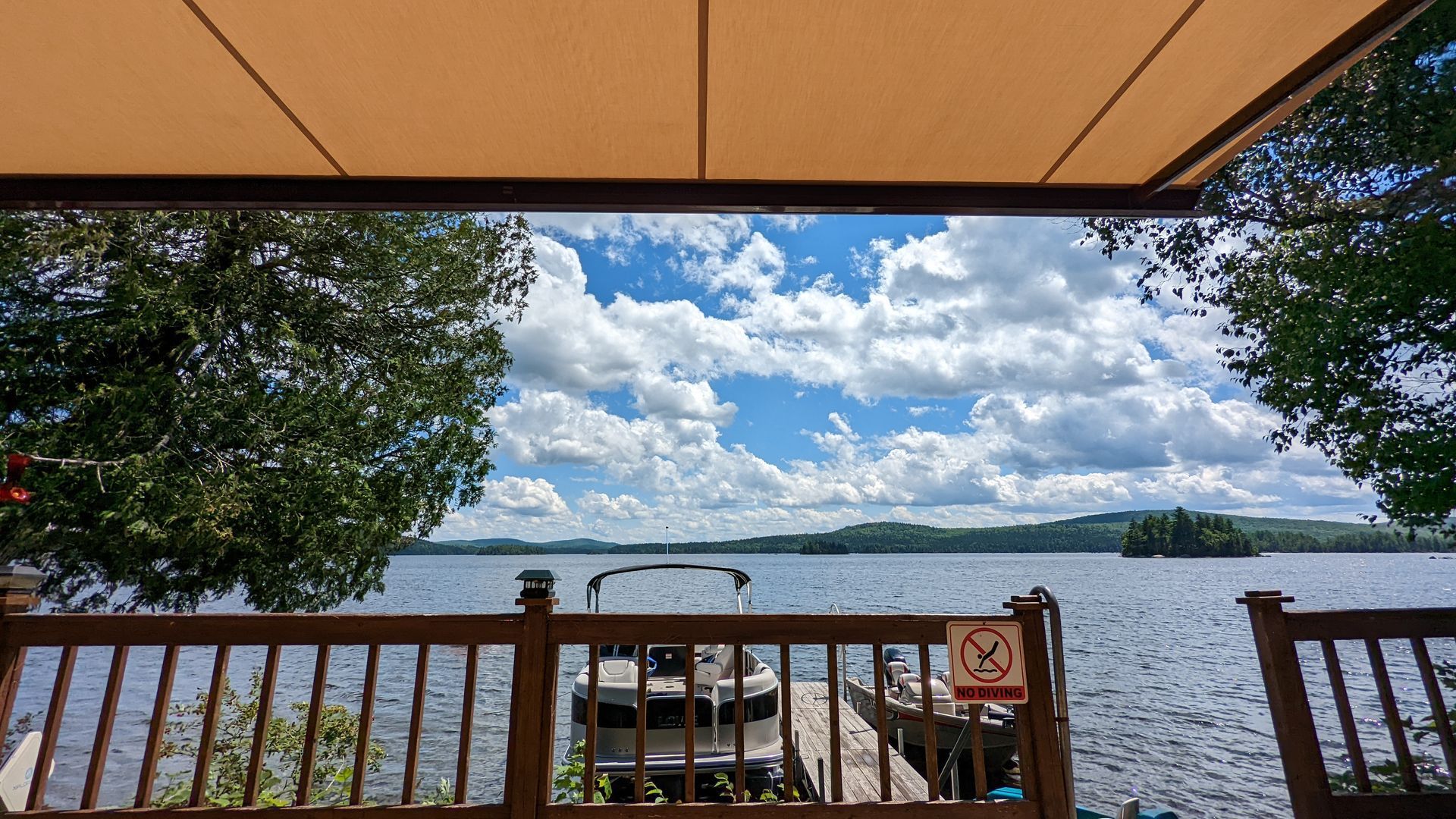 A view of a lake from a deck under an awning.