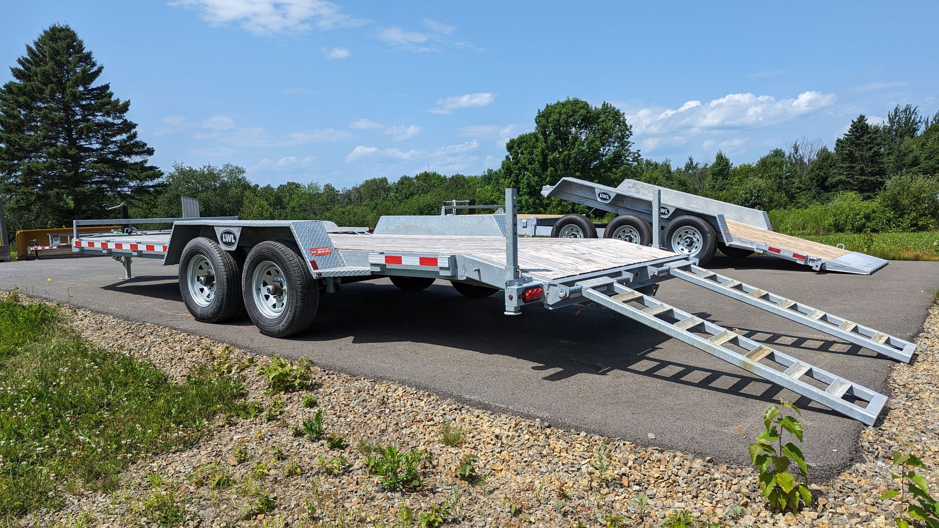 A trailer with ramps is parked on the side of a road.