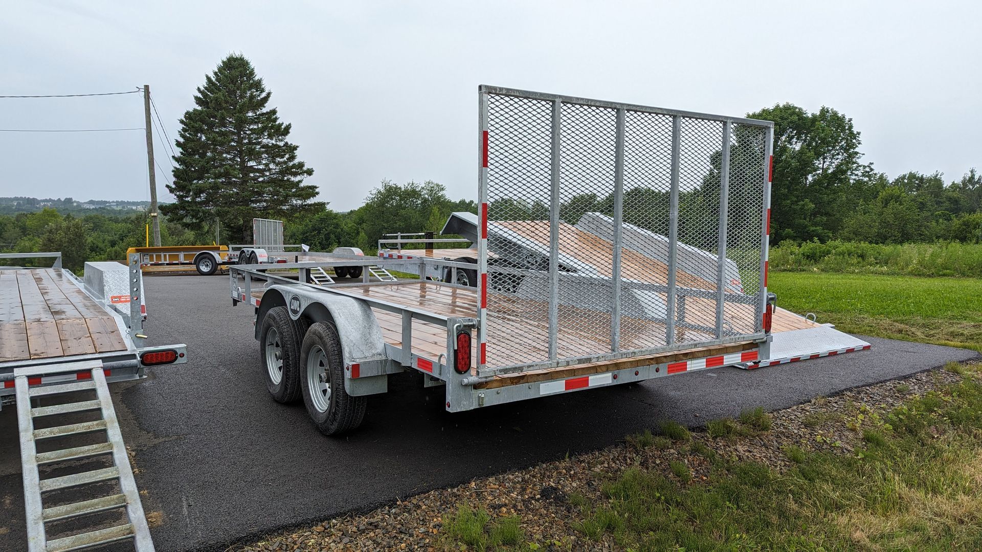 A trailer is parked on the side of the road next to a grassy field.