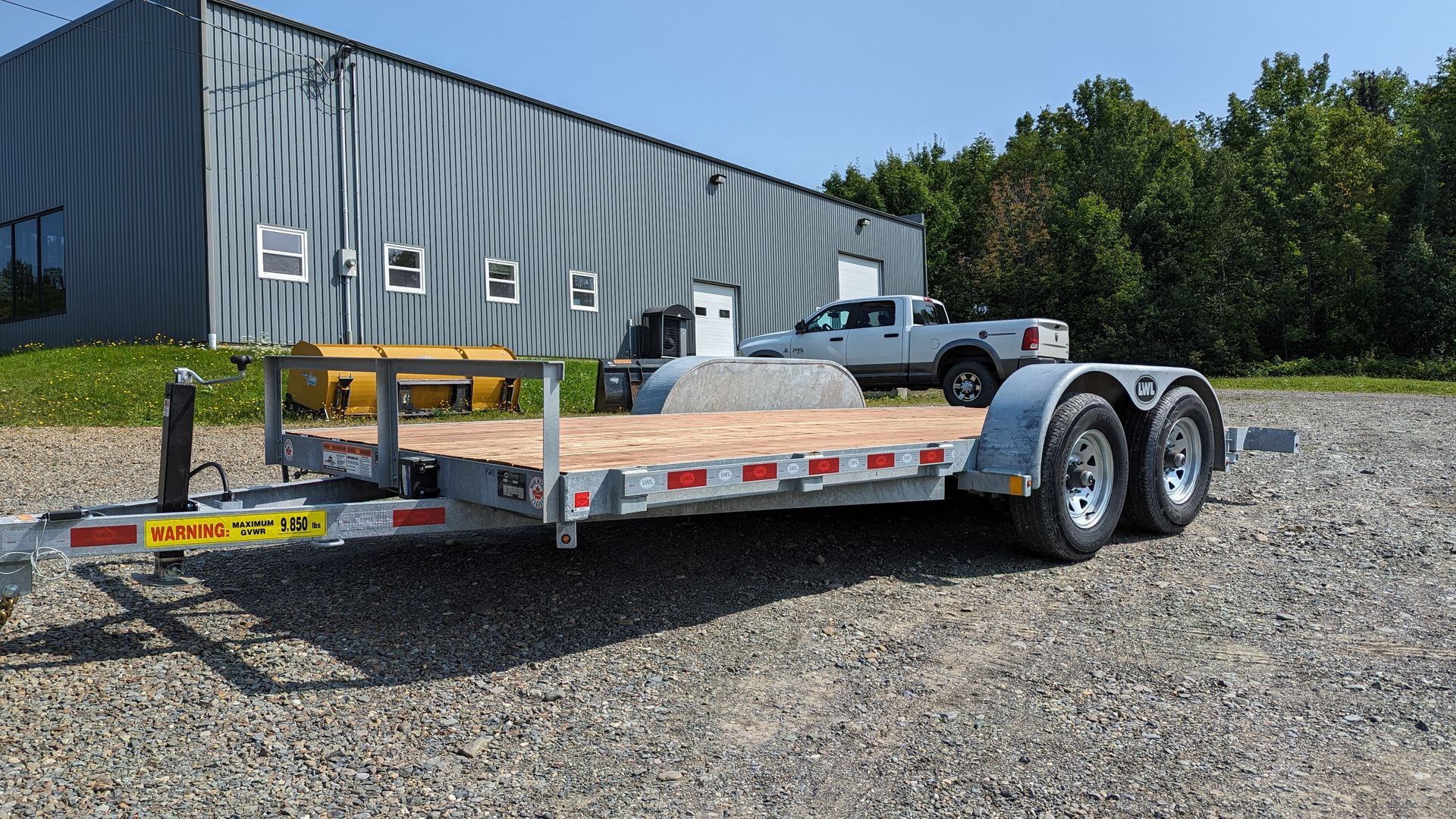 A trailer is parked in a gravel lot in front of a building.