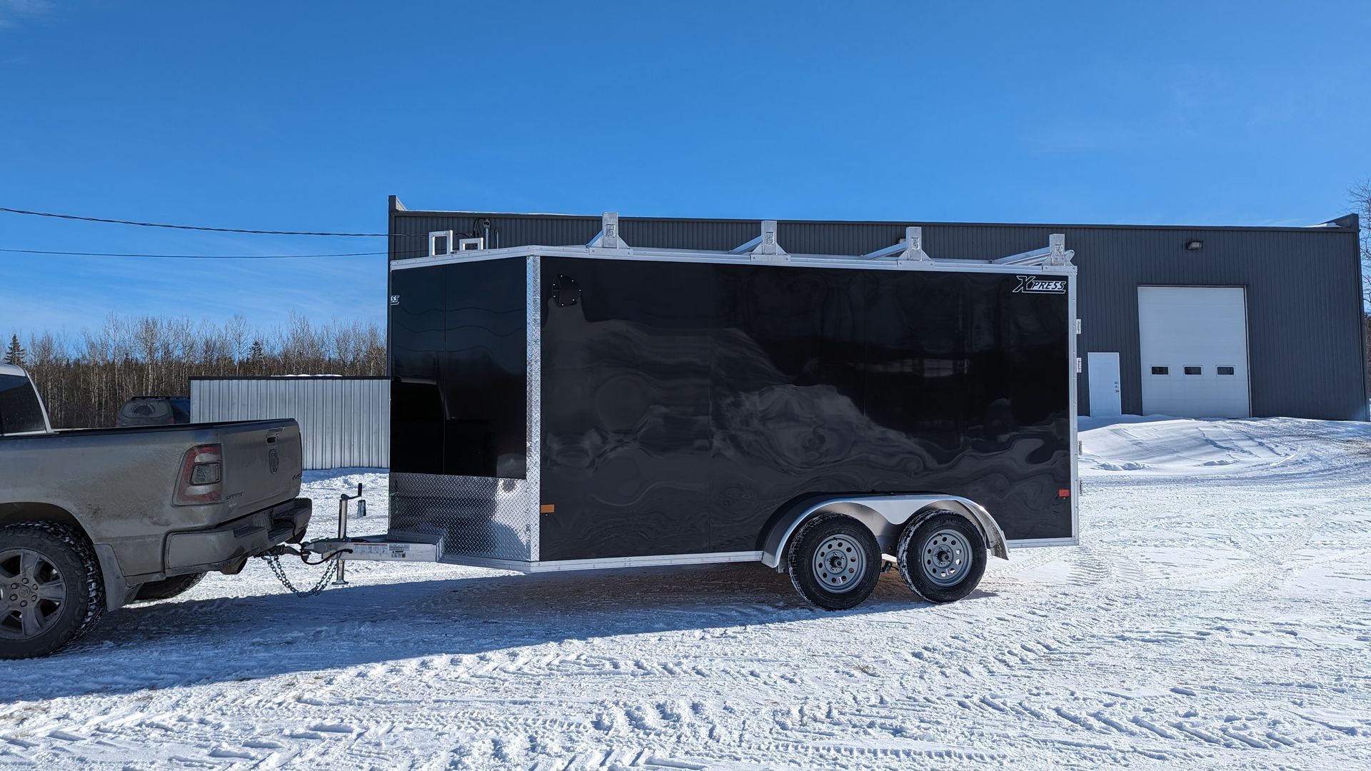 A truck is towing a black trailer in the snow.