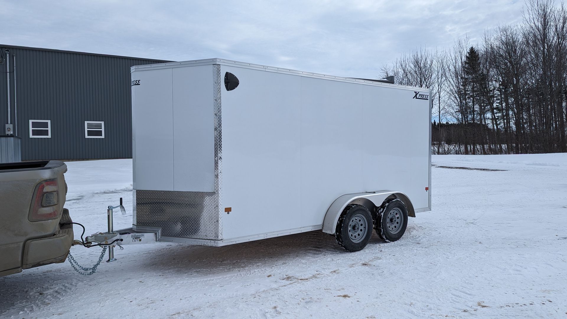 A white trailer is being towed by a truck in the snow.
