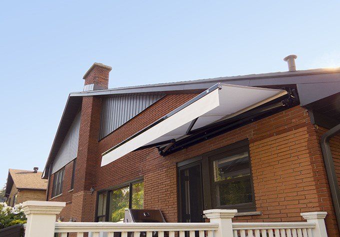 A brick house with a white awning on the side of it.