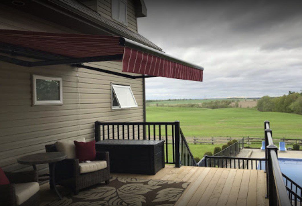 A deck with a red awning over it and a view of a field.