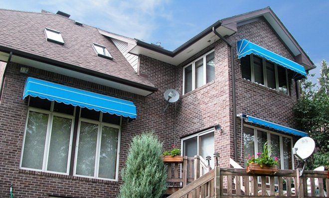 A large brick house with a blue awning on the windows