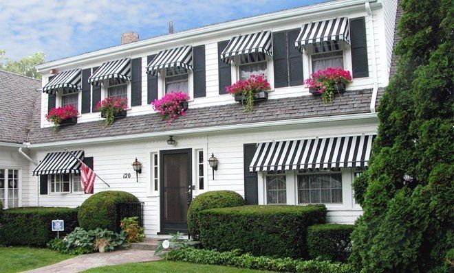 A white house with black and white awnings on the windows