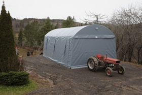A red tractor is parked in front of a large tent.