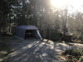 A car is parked in a garage in the woods.