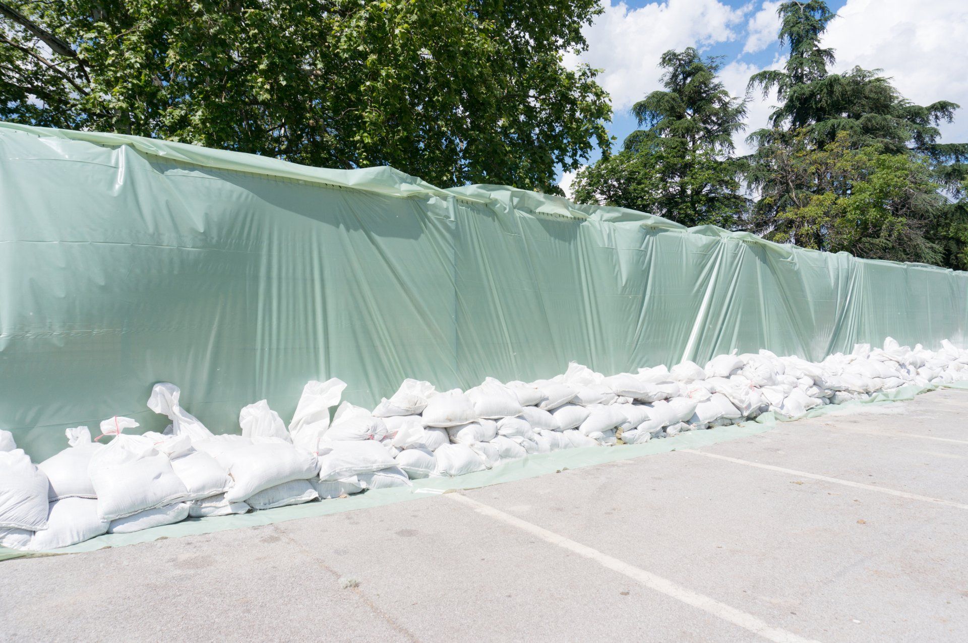 Temporary flood barrier by using geomembrane pond liner fabric and sand bags