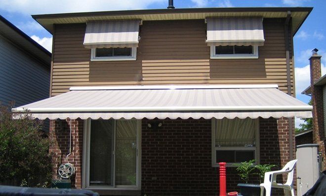 A brown house with a white awning on the porch