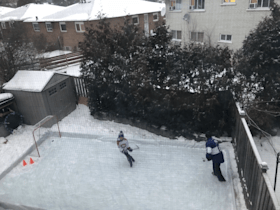 Two people are playing ice hockey in a backyard