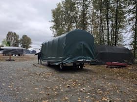 A man is covering a trailer with a tarp in a parking lot.