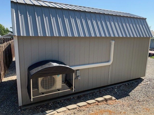 A shed with a metal roof and a small air conditioner on the side