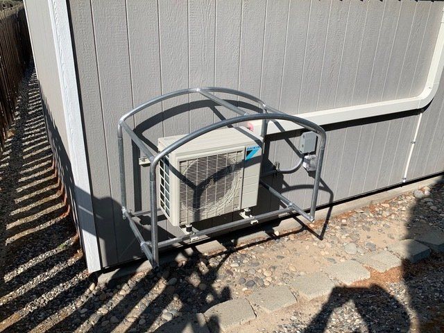 An air conditioner is sitting on a metal stand outside of a building.