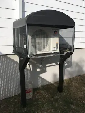 An air conditioner is mounted to the side of a house