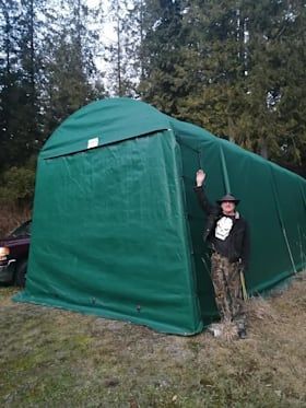 A man is standing in front of a green tent.