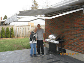A man and a woman are standing in front of a grill.