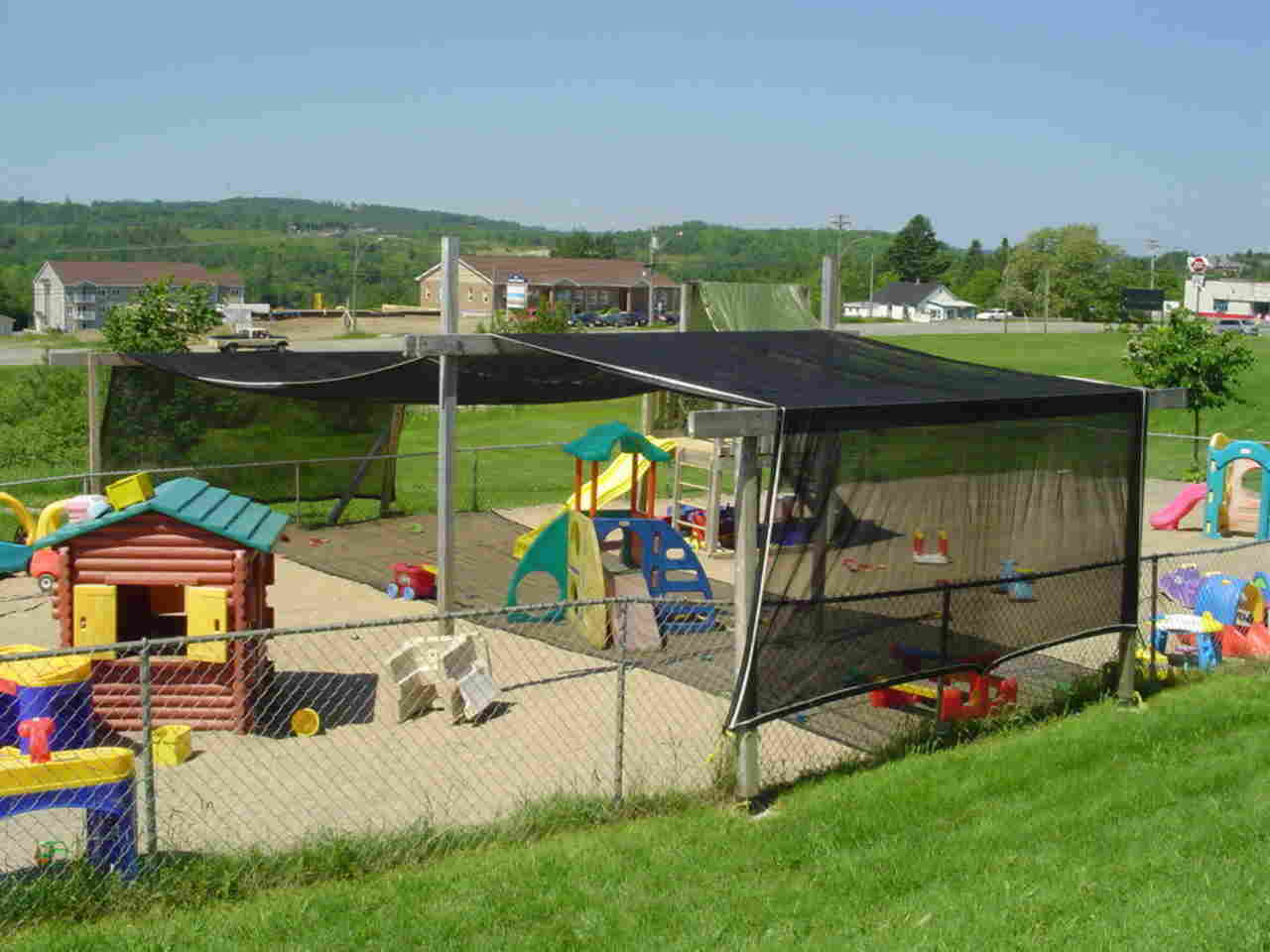 A playground with a fence and a shade structure