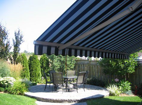 A black and white striped awning over a patio with a table and chairs