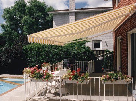 A yellow and white awning over a patio next to a pool