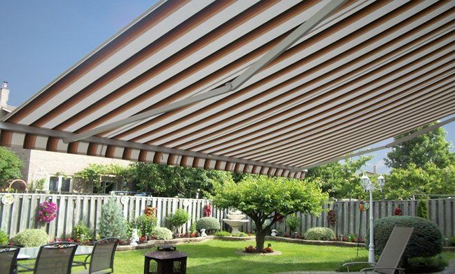 A large awning is covering a patio in a backyard.