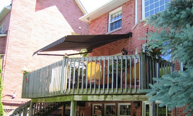 A brick house with a large deck with a canopy over it.