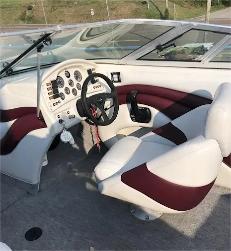 Boat interior: white and maroon seats, steering wheel, dashboard, and gauges.