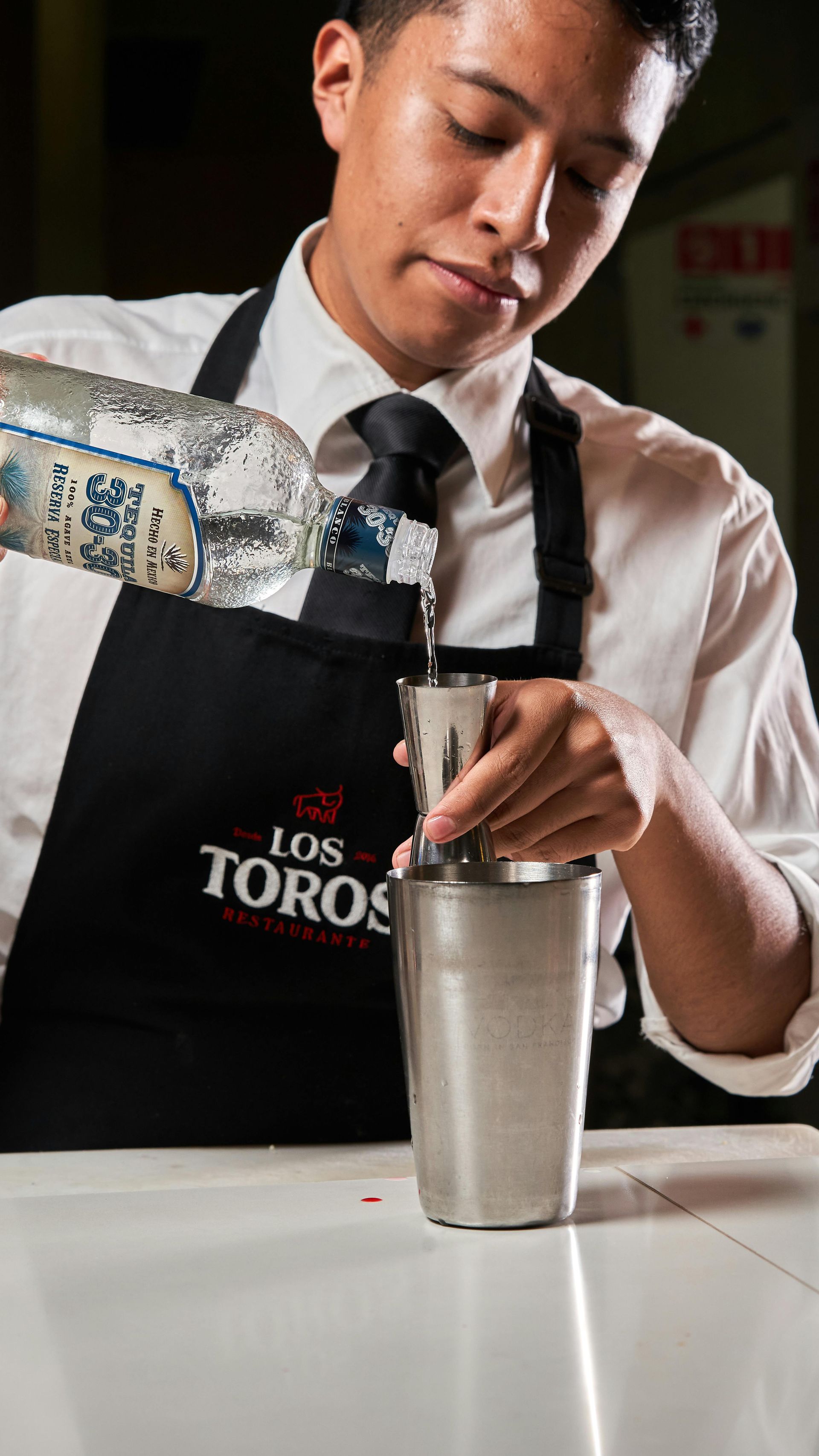 A bartender wearing a black apron with 