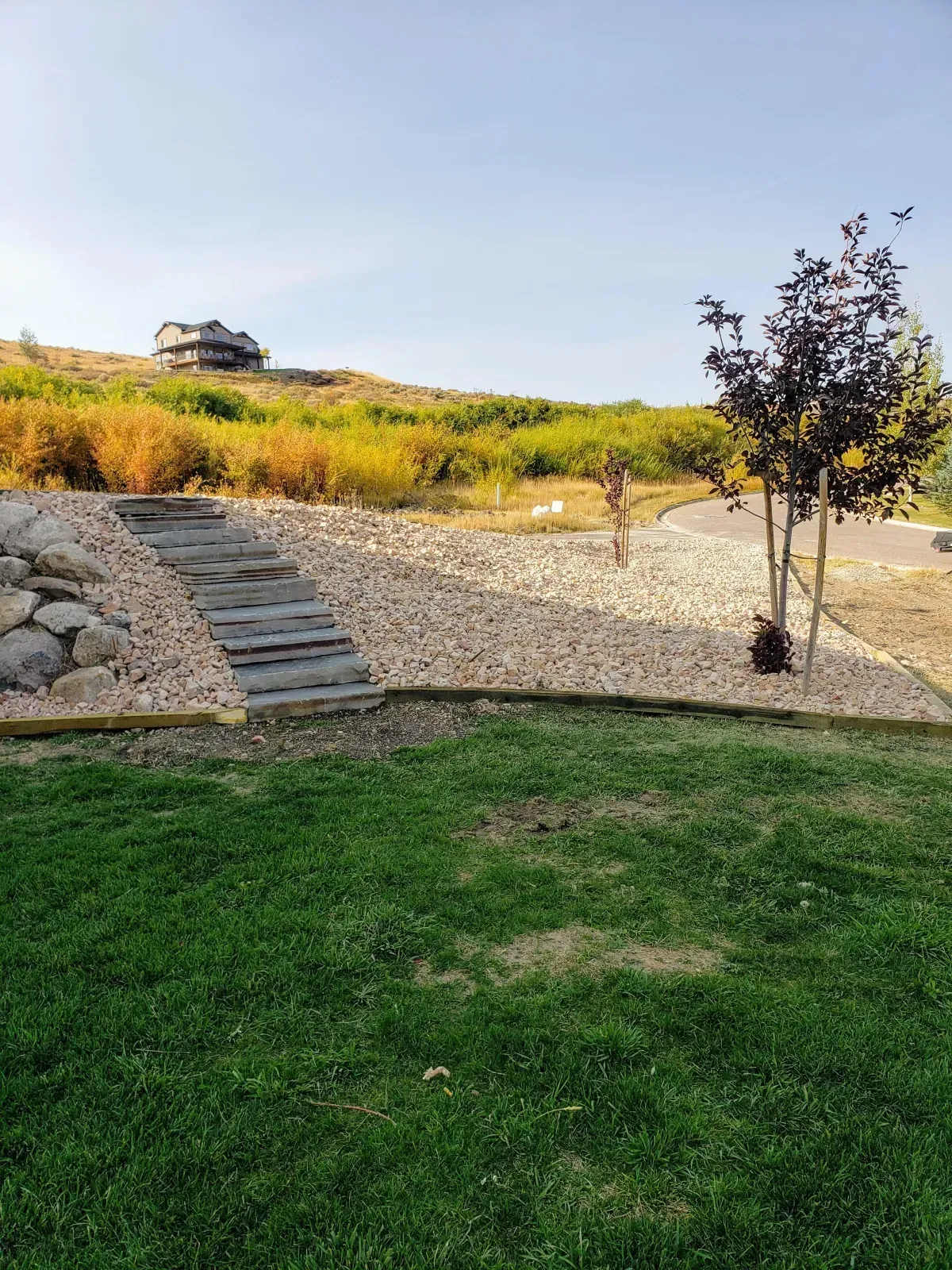 A Lush Green Lawn with Stairs Leading up To a House on A Hill.