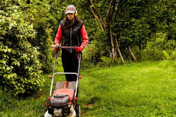 A Woman Is Using a Lawn Mower to Cut the Grass.