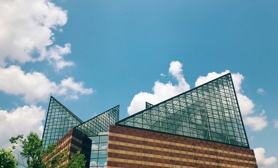 Brick building with glass triangular roof against a blue sky with white clouds.