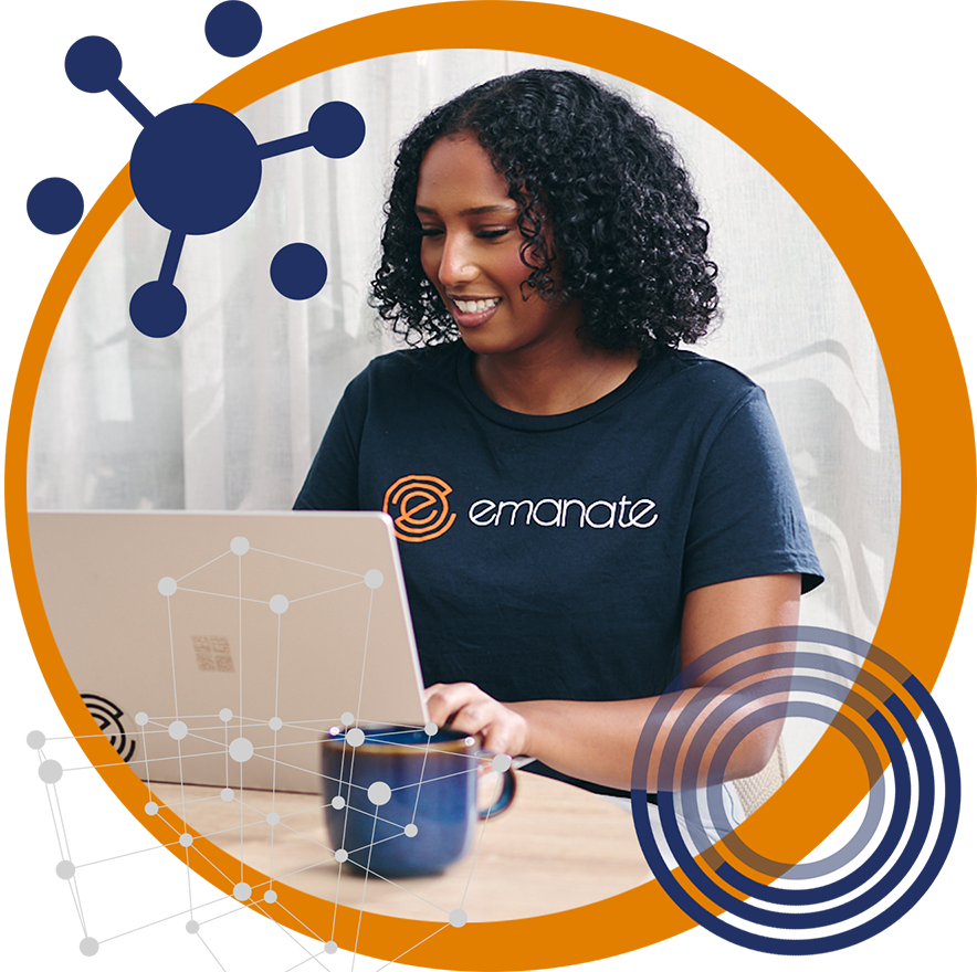 A woman wearing an emanate shirt is typing on a laptop