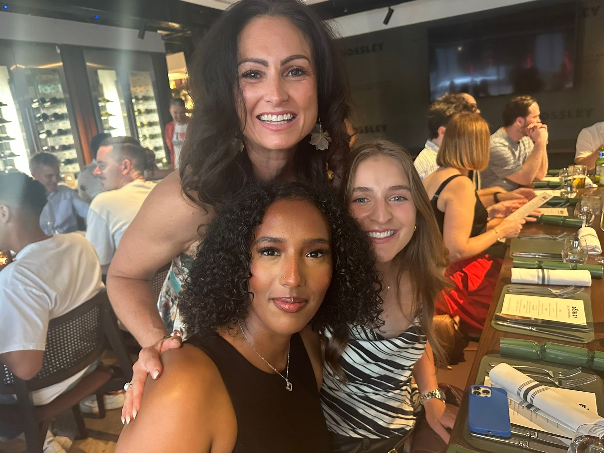 Three women are posing for a picture in a restaurant.