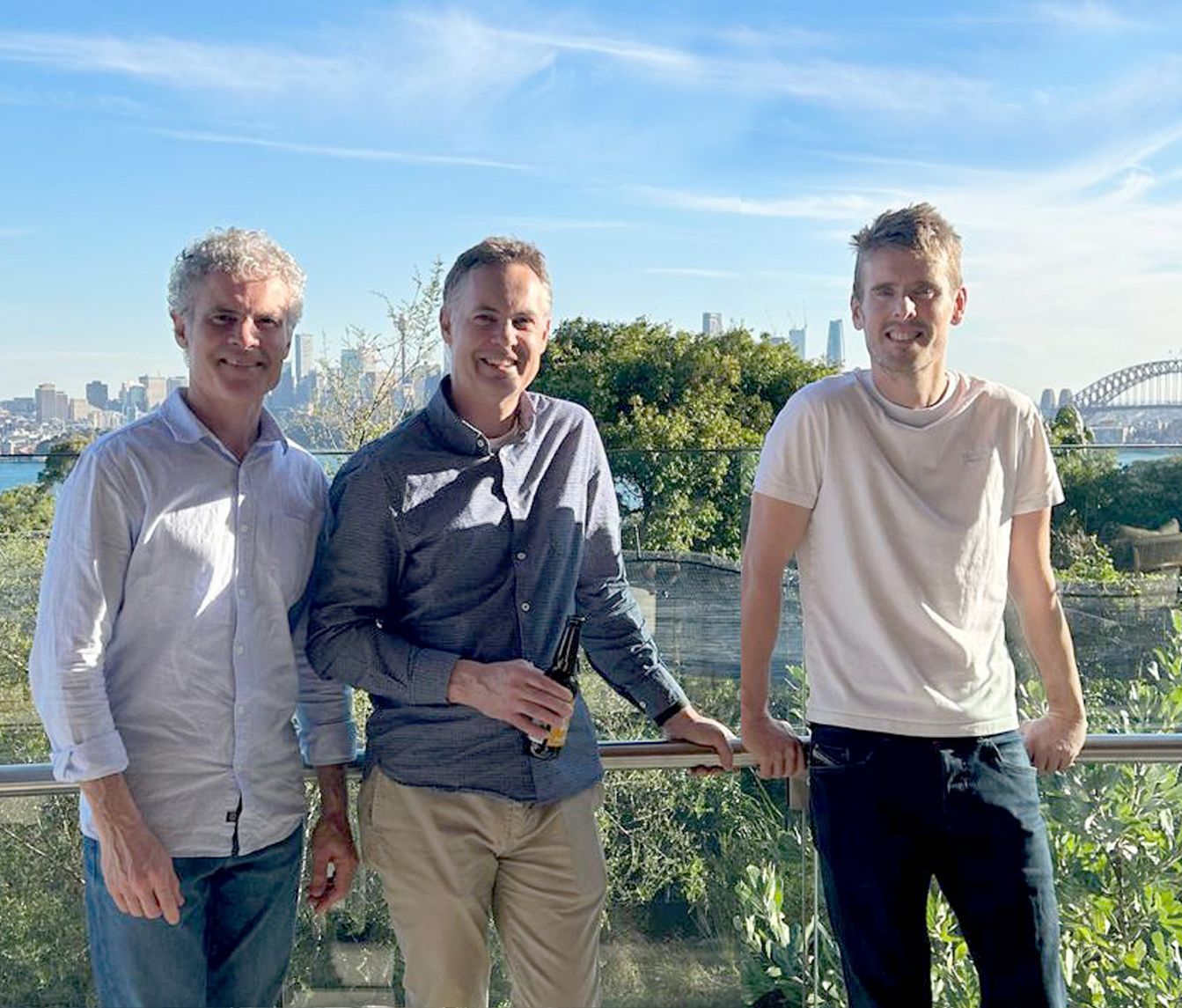 Three men are standing next to each other on a balcony.