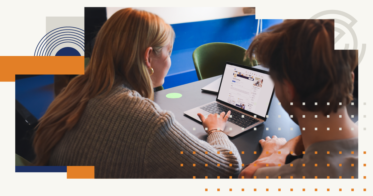 A man and a woman are sitting at a table looking at a laptop.