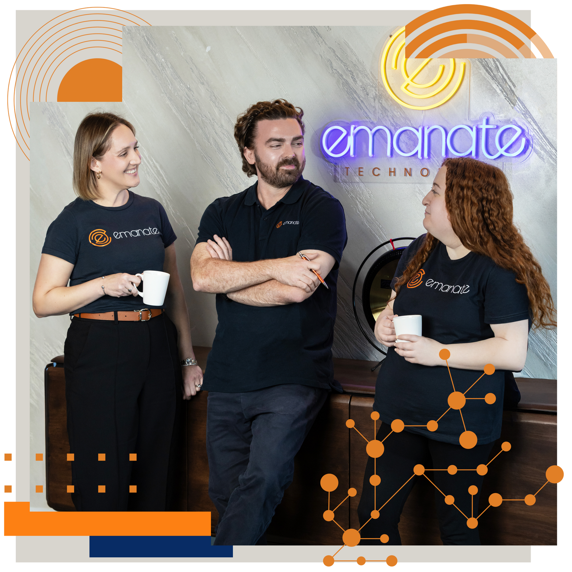 Three people in branded navy shirts stand in an office with an 