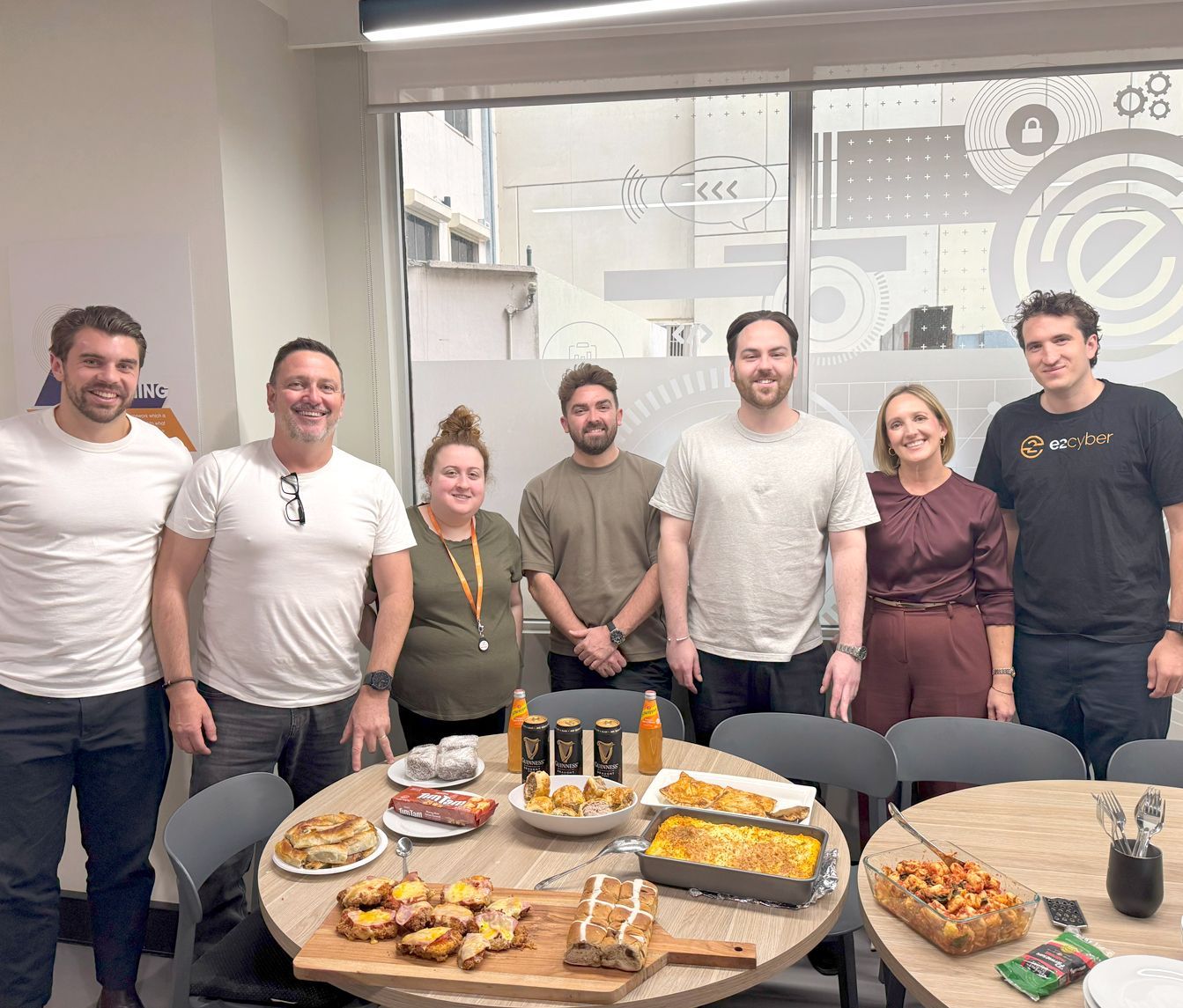 A group of people are standing around a table with food on it.