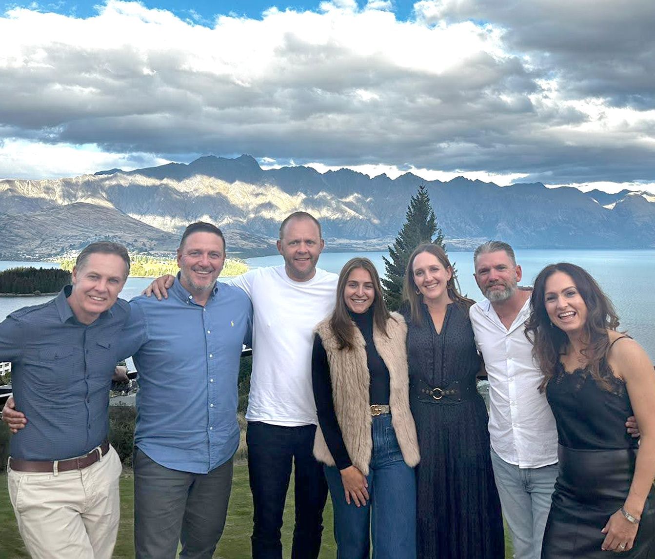 A group of people posing for a picture with mountains in the background.