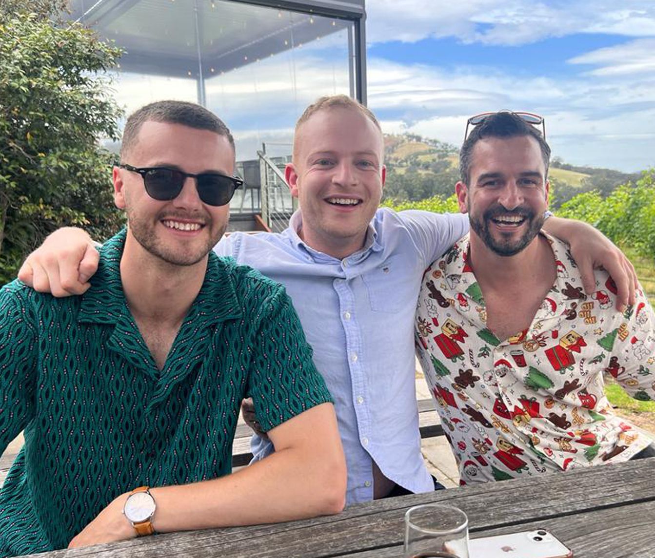 Three men are posing for a picture while sitting at a table.