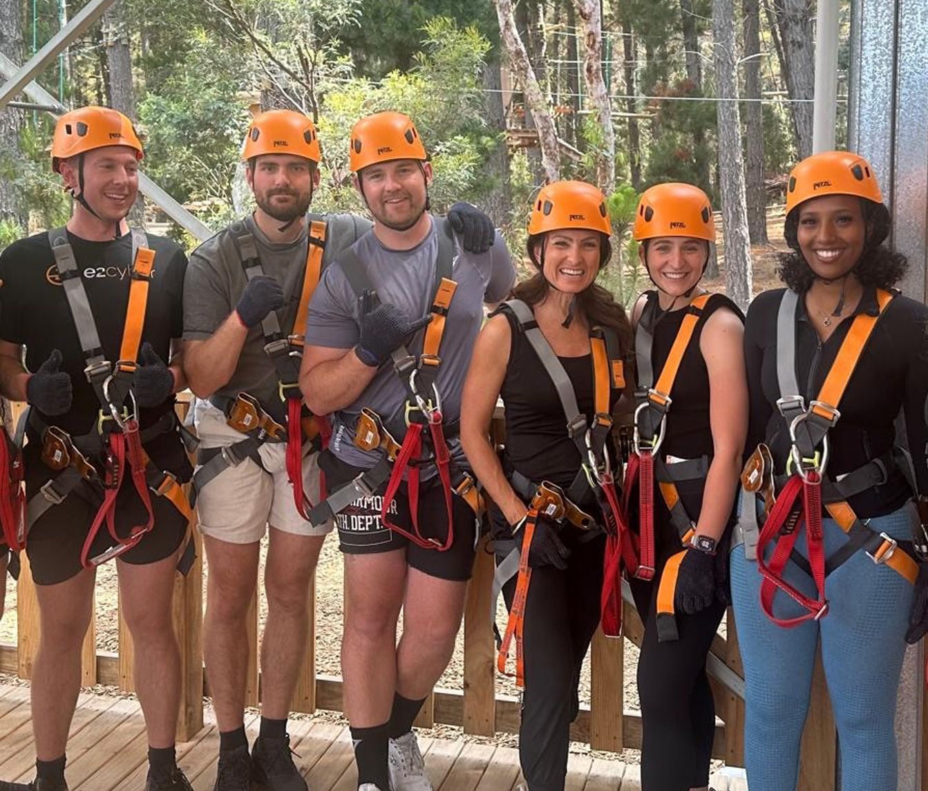 A group of people wearing helmets and harnesses pose for a picture