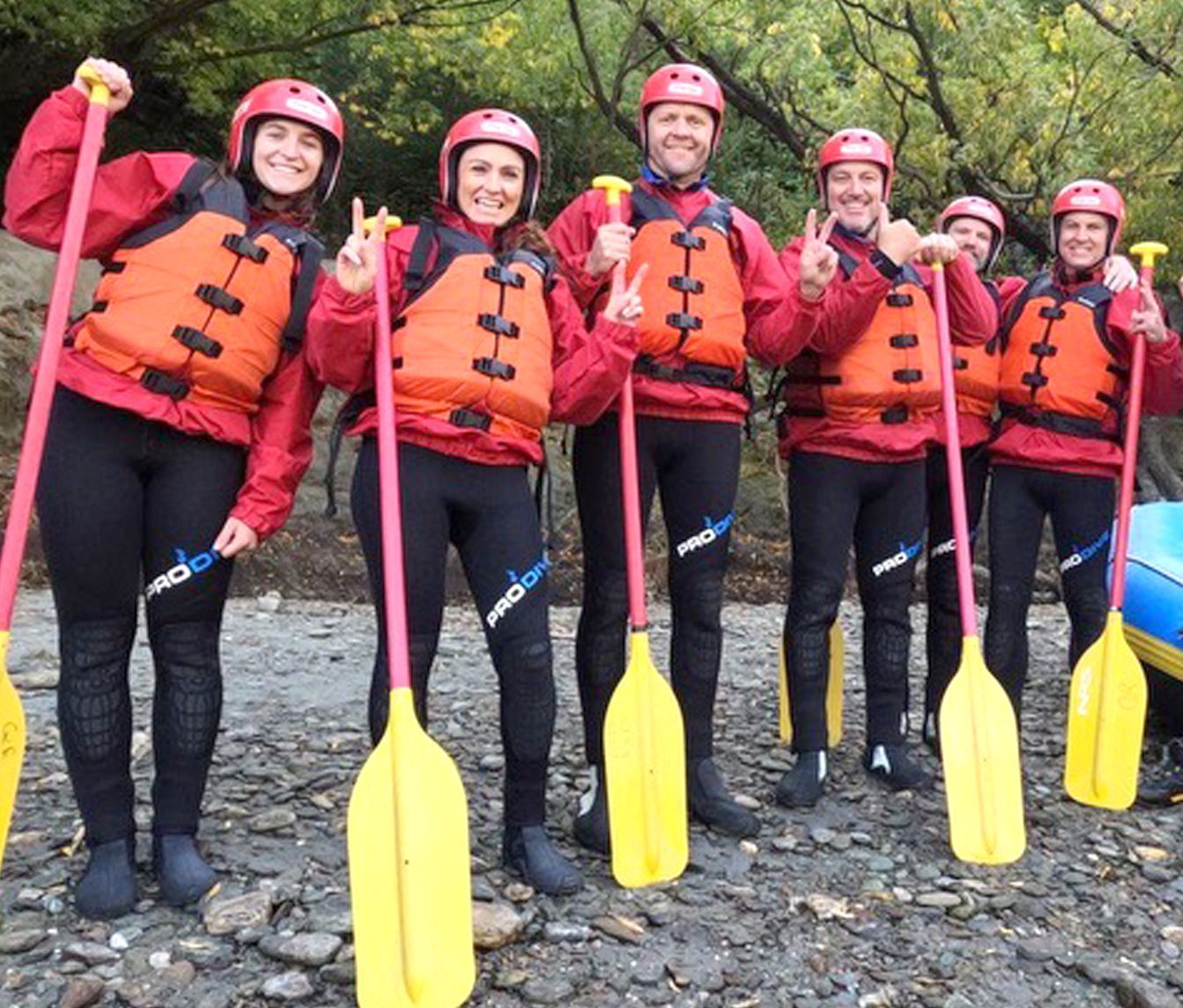 A group of people wearing life jackets and holding yellow oars